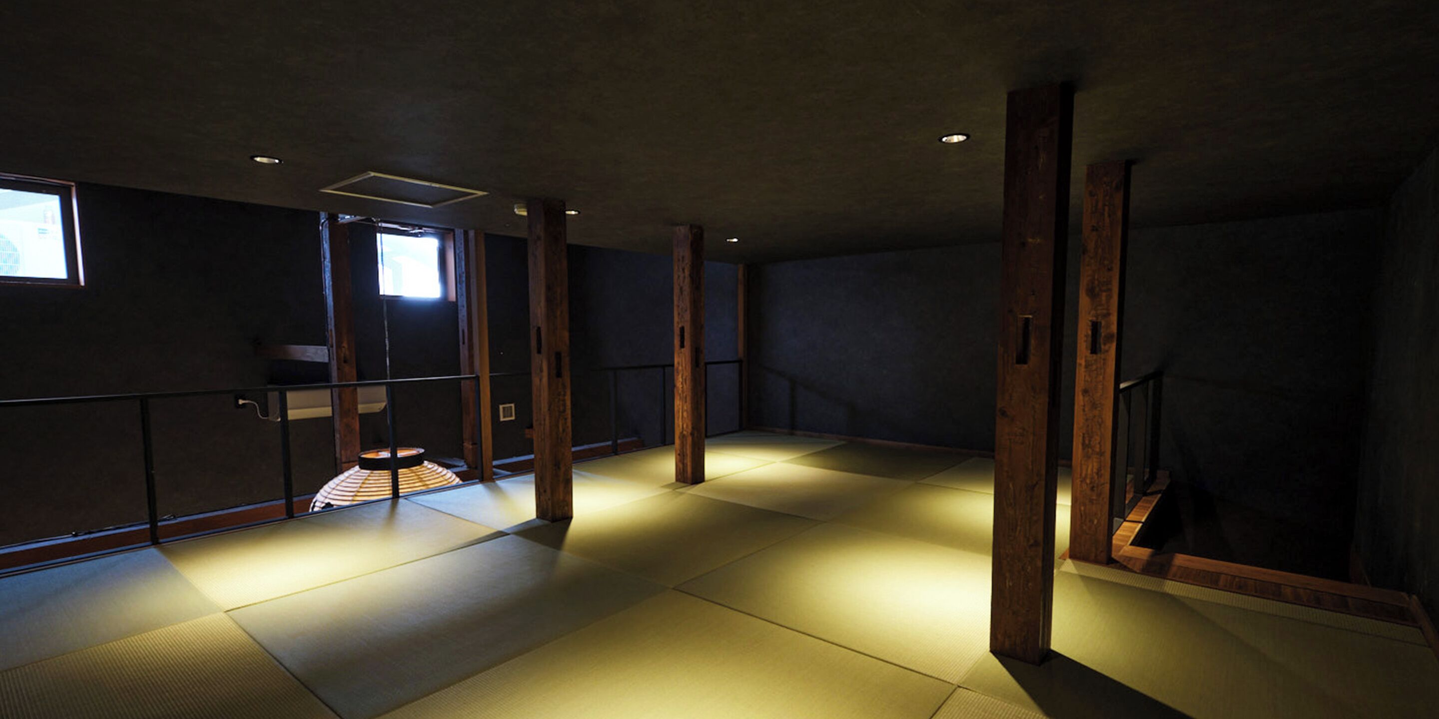 Une pièce dotée d’un sol recouvert de tatamis, de poutres en bois et d’une porte coulissante donnant accès à une salle de bain.