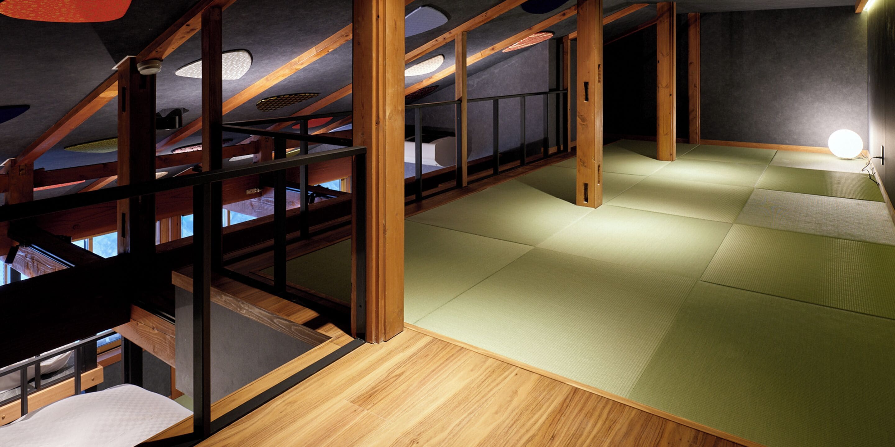 A room with a wooden floor, tatami mats, and a low ceiling with exposed beams.