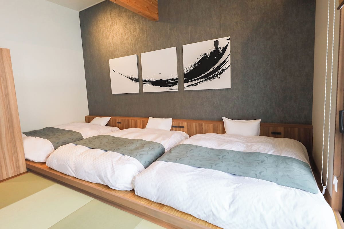 A hotel room with a large bed, wooden wardrobe, and a wall with abstract art.