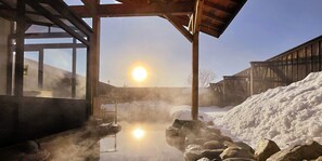 A sauna area with a stone bench, a wooden structure, and a large pile of snow. - Hakuba Ryujin Onsen RYOKAN SUI (Hakuba)