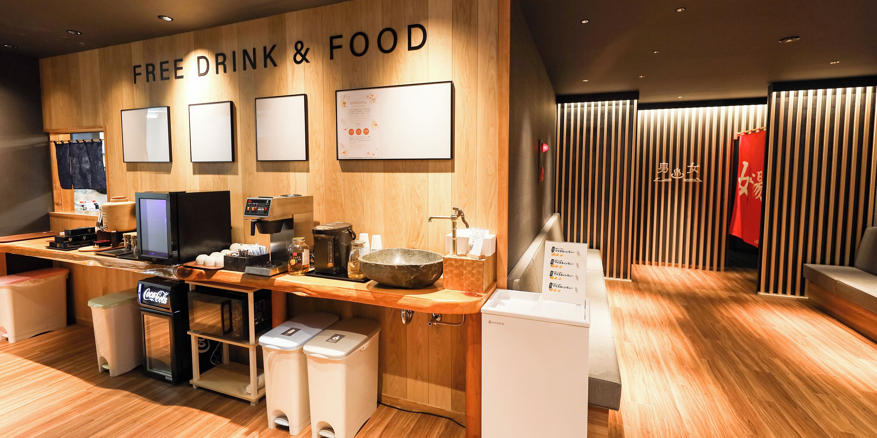 A modern kitchen area with a wooden countertop, a coffee machine, a bowl, and a refrigerator.