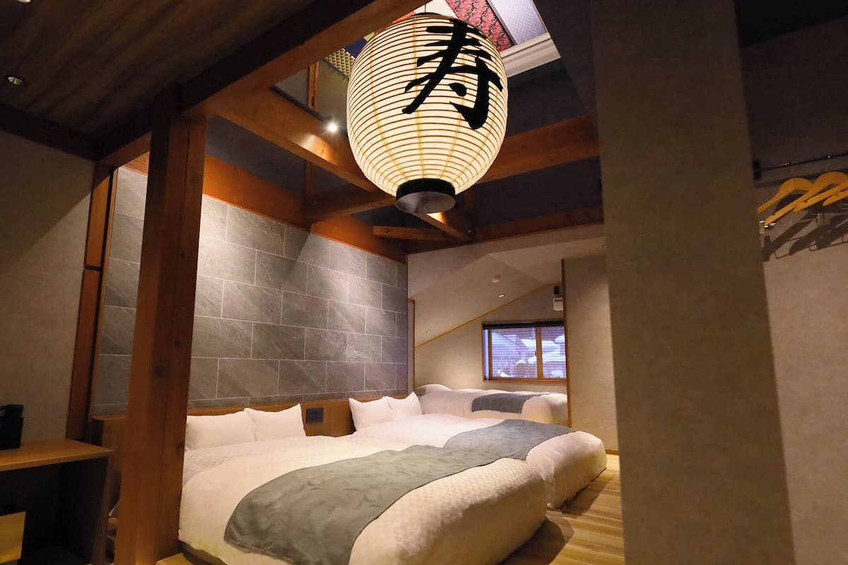 A room with a large bed, wooden beams, a lantern, and a window with a view.