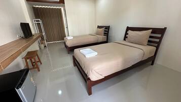 A hotel room with two beds, a desk, a chair, and a refrigerator.