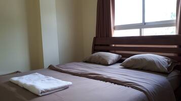 A neatly made bed with a white towel, a wooden headboard, and two pillows.