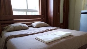 Una cama bien hecha con tablero de madera, una toalla doblada y dos almohadas.
