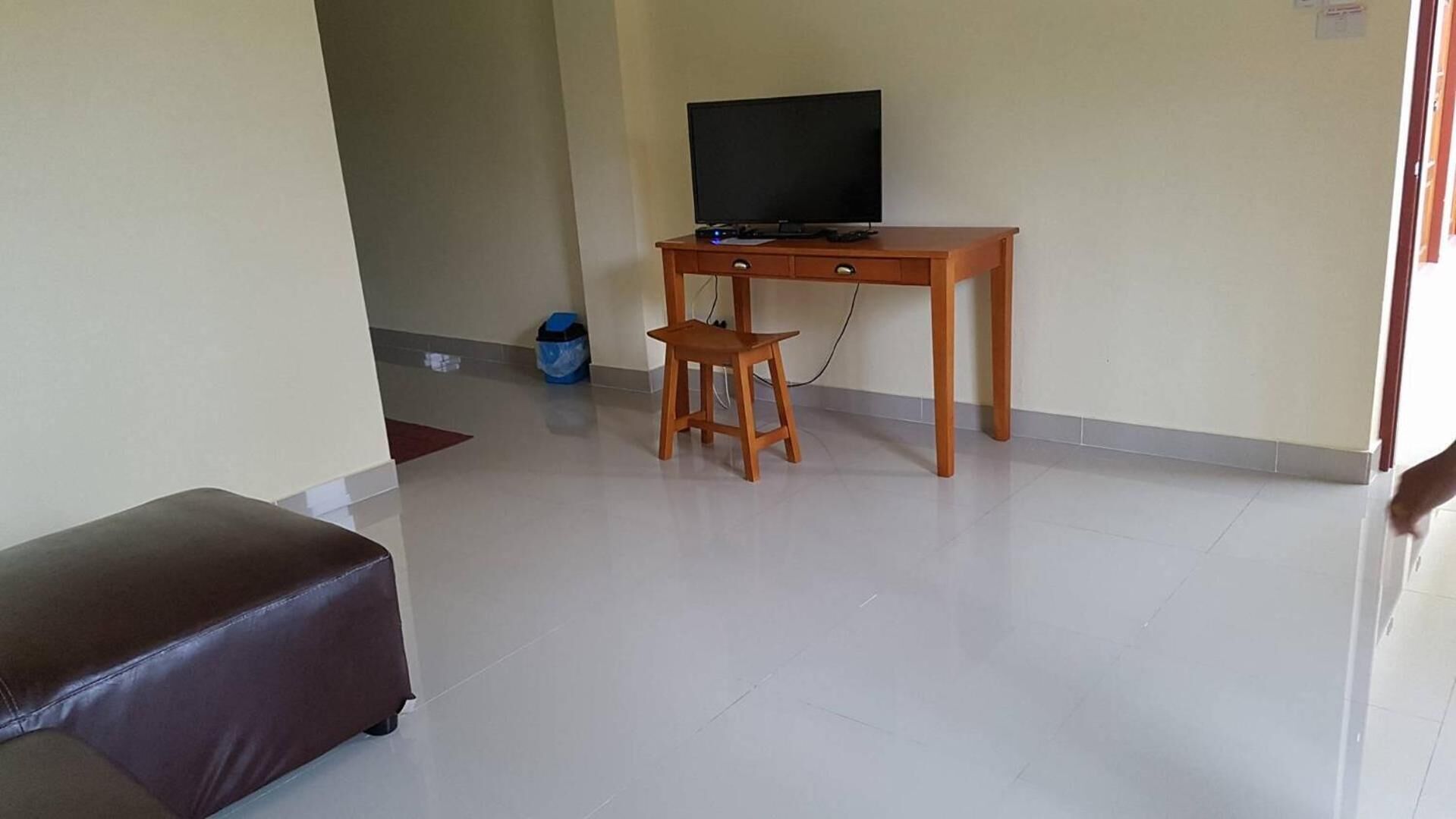 A room with a wooden desk, a television, and a small stool.