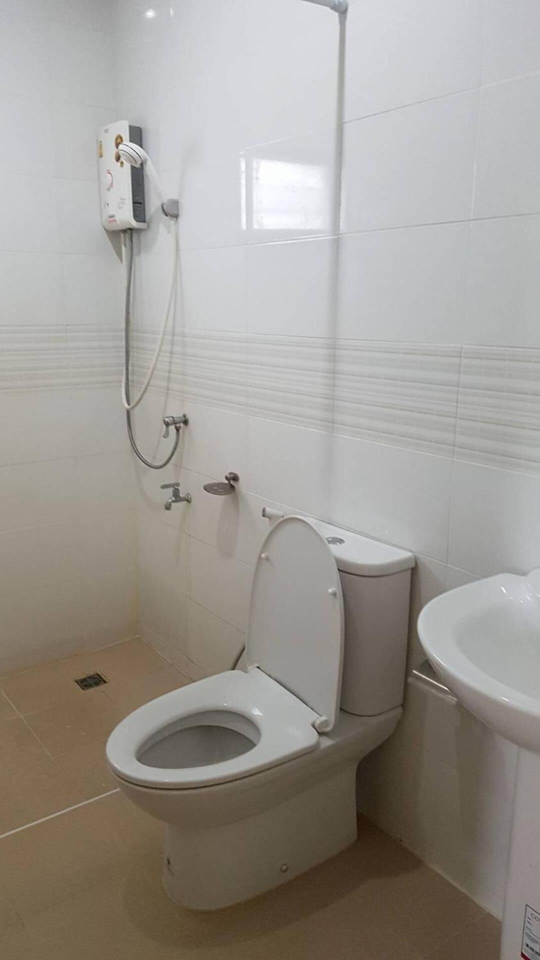 Un baño pequeño y blanco con inodoro, ducha y lavamanos.