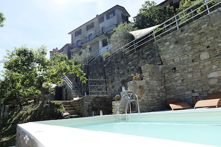 Una piscina al aire libre, sombrillas, sillones reclinables de piscina