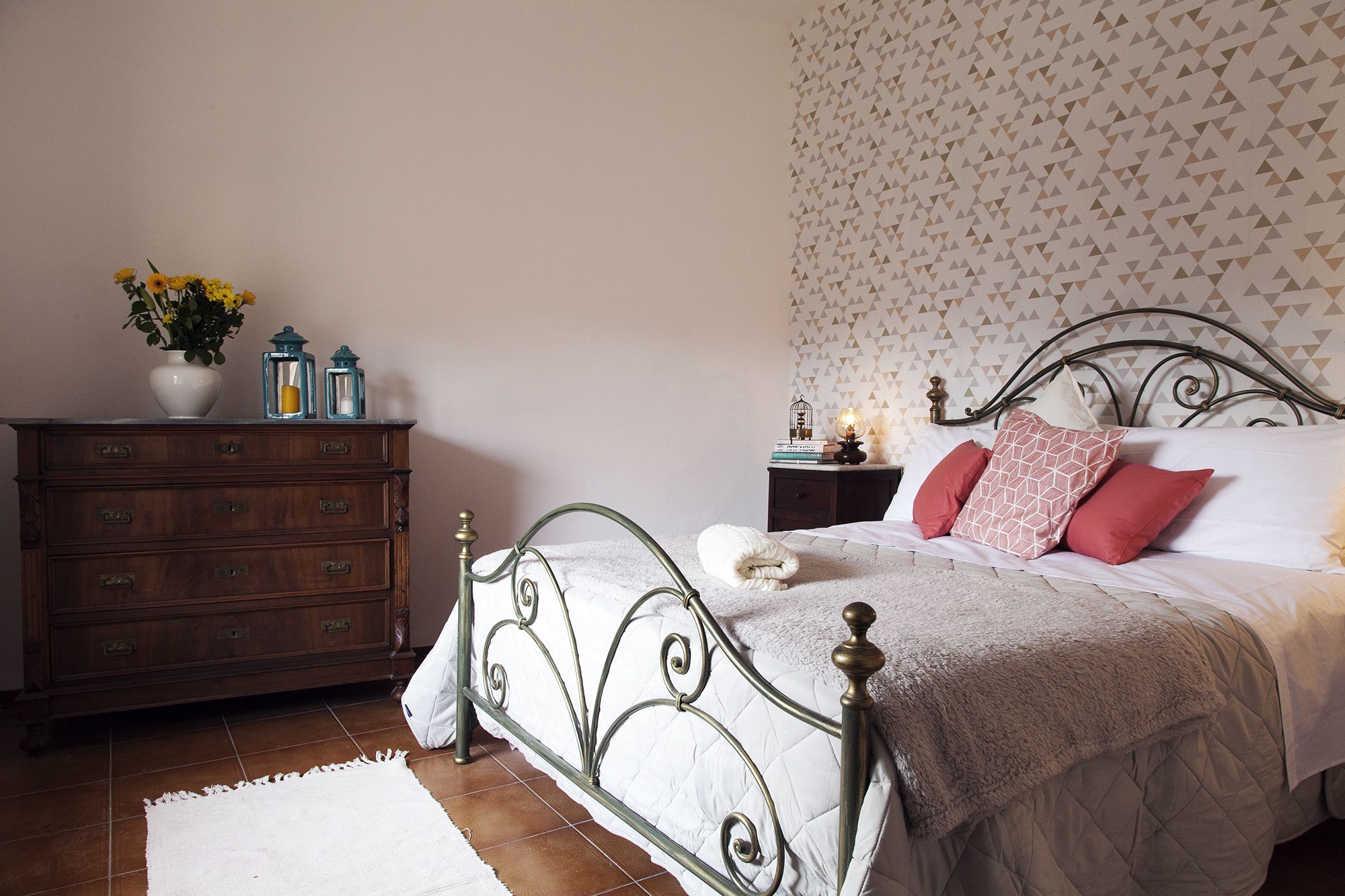 A bedroom with a bed, dresser, nightstand, and decorative items.