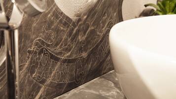 A bathroom with a marble wall featuring an embossed design and a white sink.