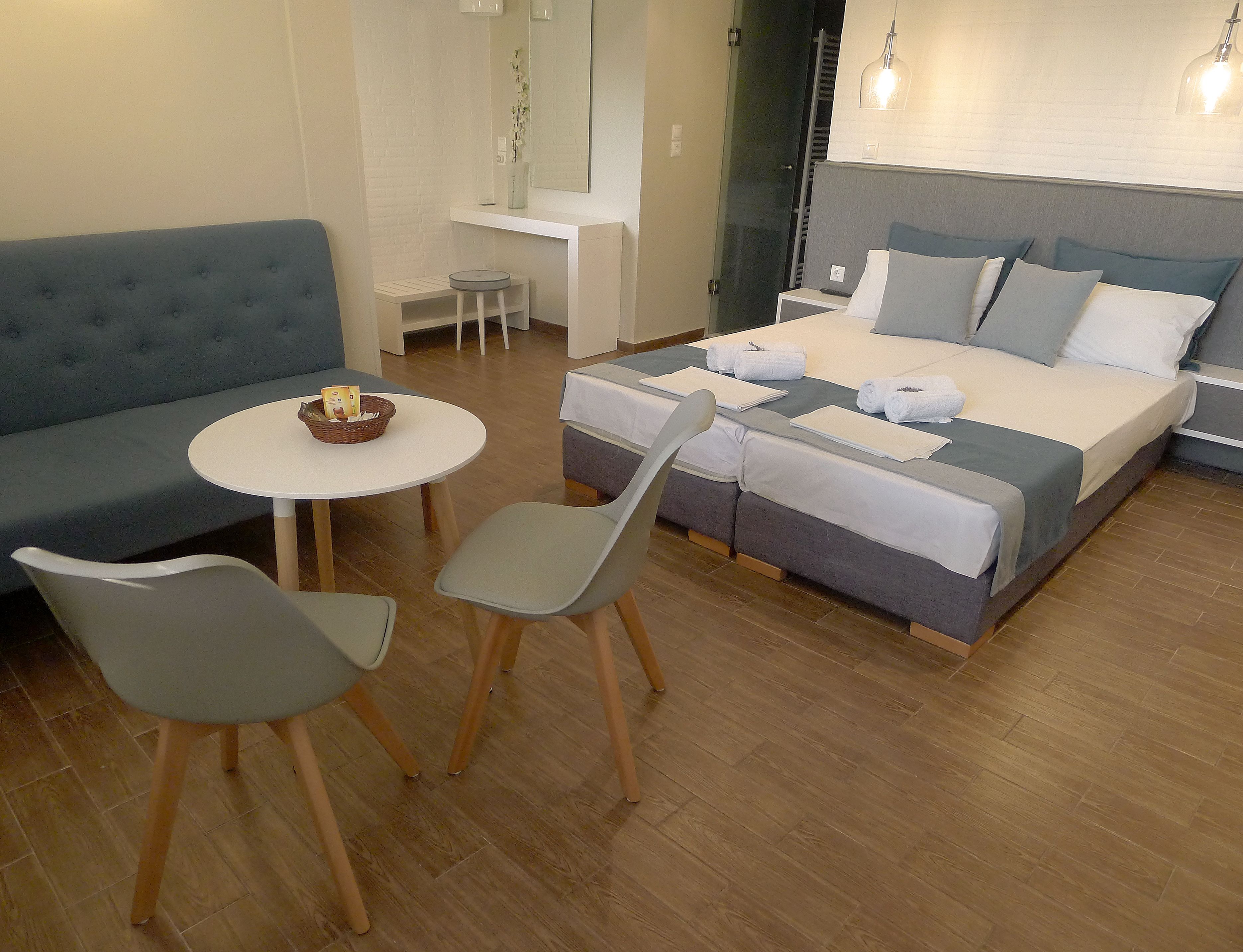 Una habitación de hotel moderna con una cama, un sofá, una pequeña mesa redonda con una cesta y dos sillas.
