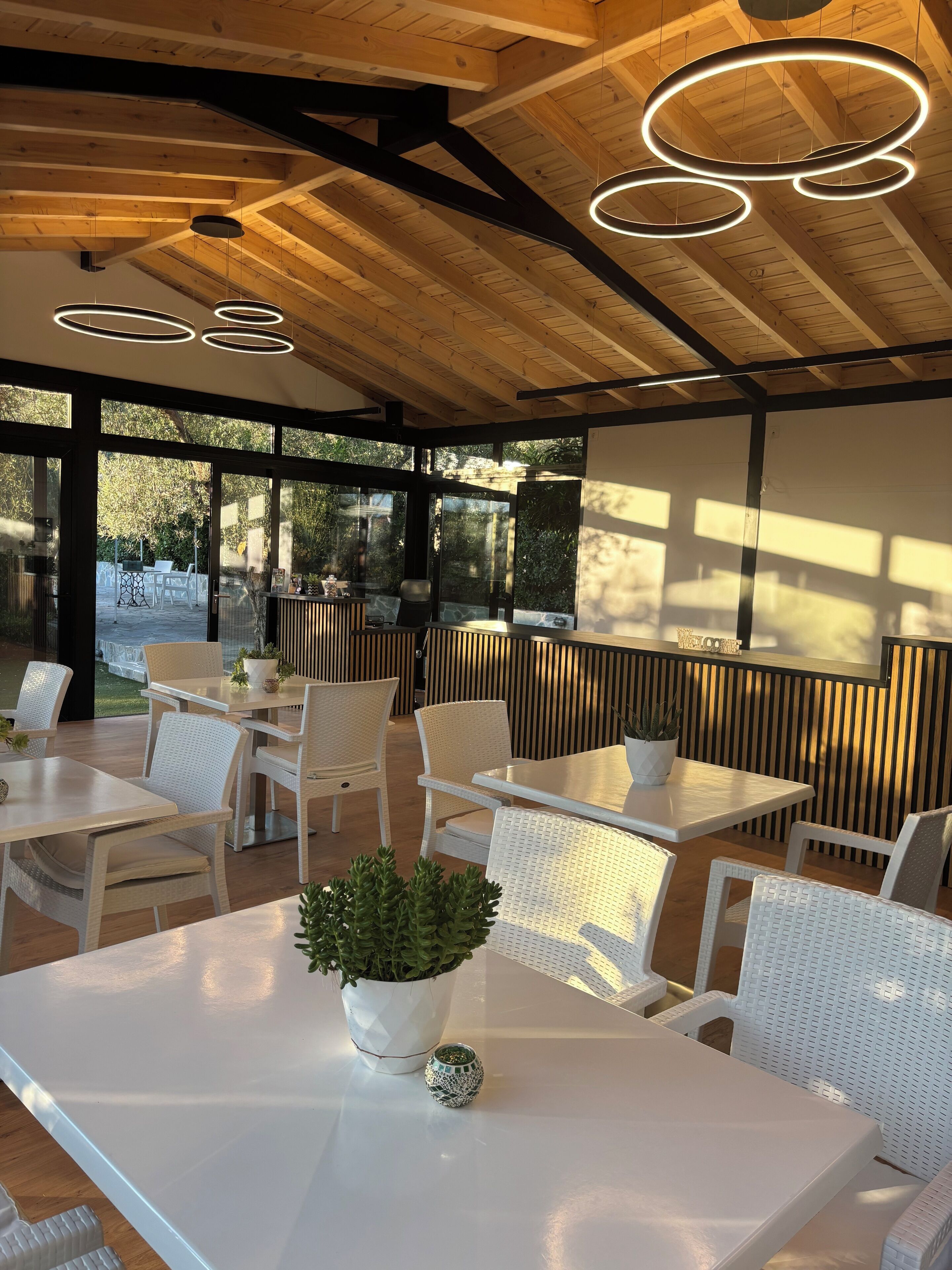 Un espacio de comedor al aire libre con mobiliario de mimbre blanco y una planta en maceta.