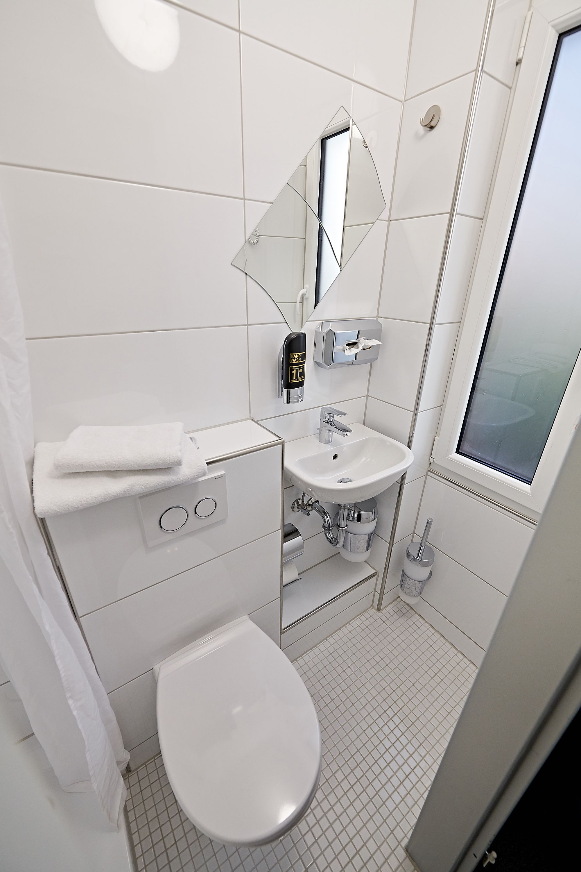 A modern bathroom with a white sink, mirror, and toilet.