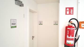 Un pasillo con puertas identificadas con los números 10 y 11, un extintor de incendios montado en la pared, y un letrero que indica zona privada.