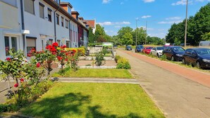 A residential street with parked cars, a grassy median, and a row of townhouses with shutters. - Aparthotel Jonas (Bremen)