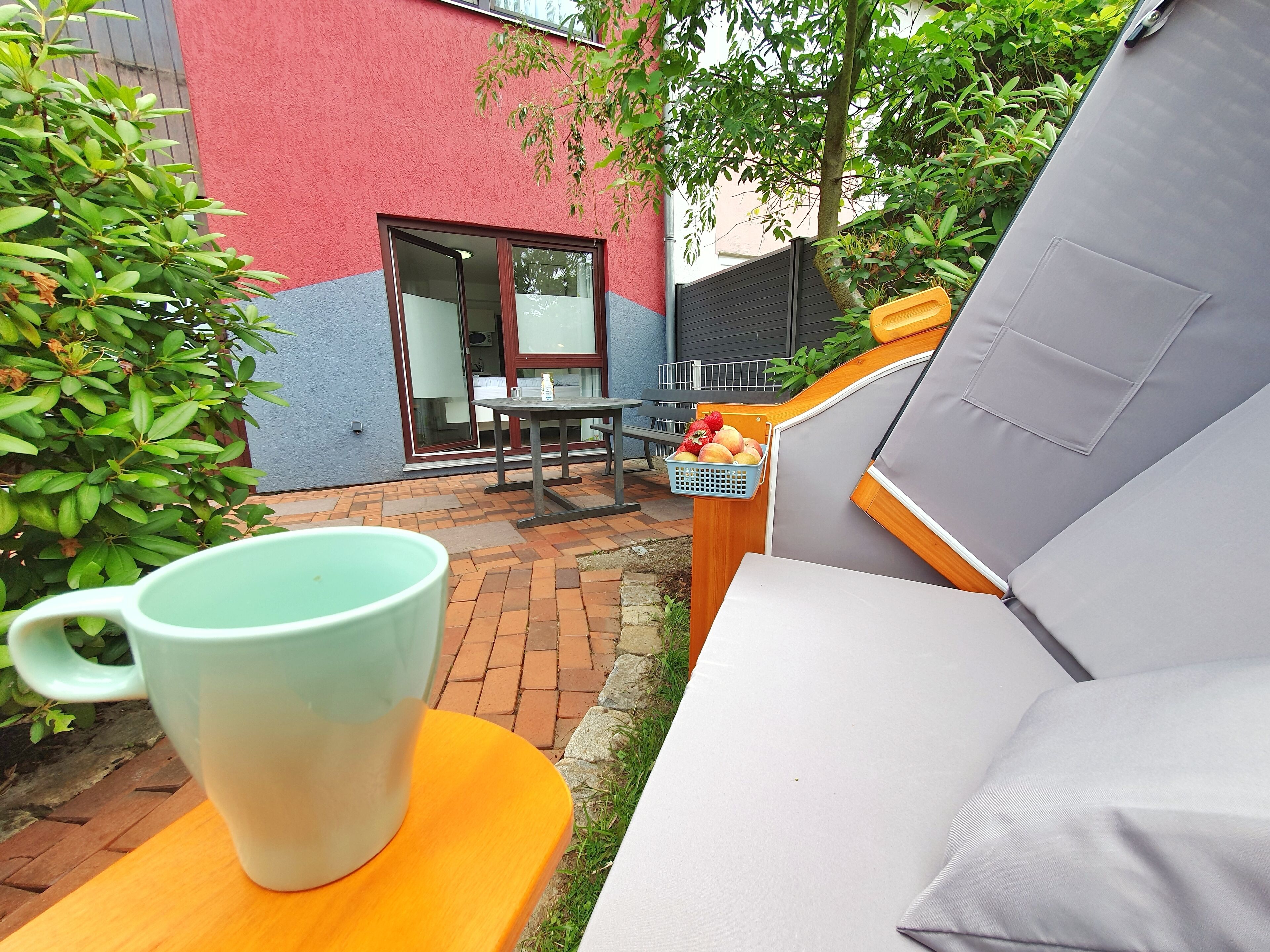 Eine Terrasse mit Tisch und Stühlen, einer großen Tasse und einem Obstkorb.