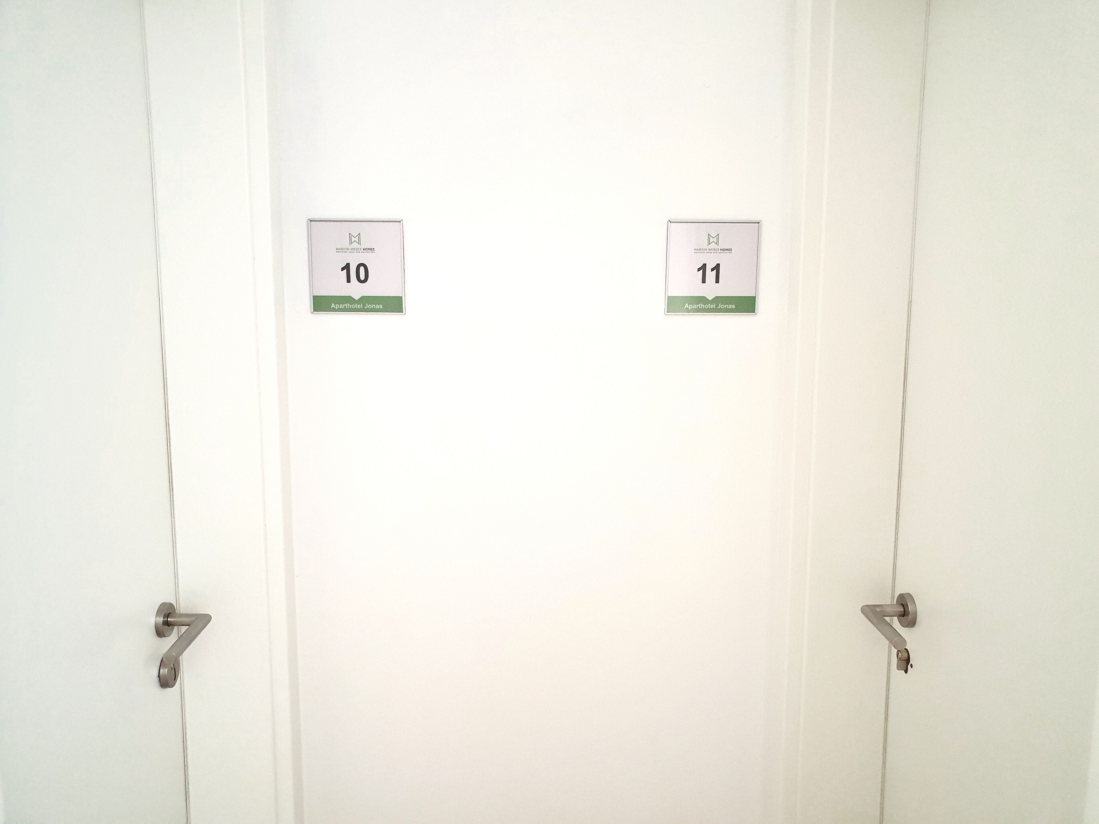 To hvide døre med nummer 10 og 11, der angiver separate værelser, og et metalgreb på hver dør.