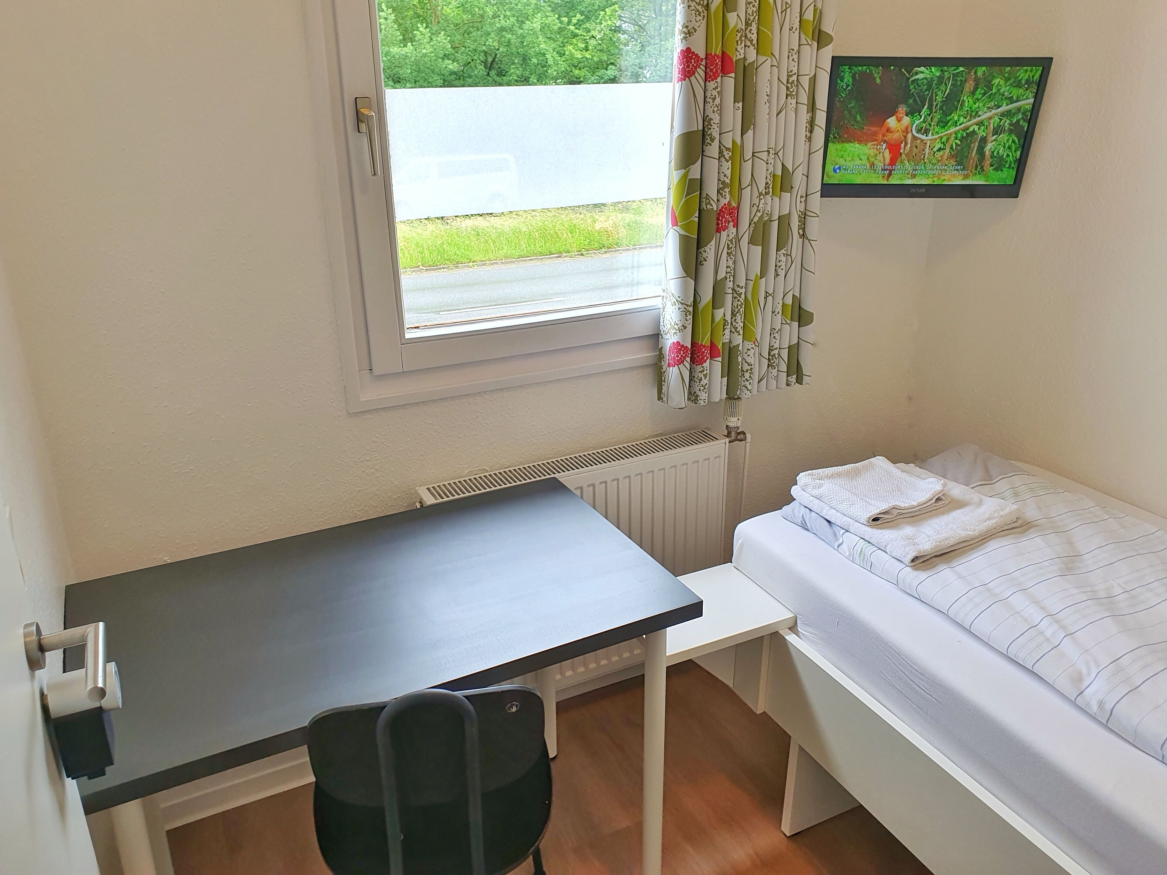 Una habitación pequeña con una cama individual, un escritorio y una silla.