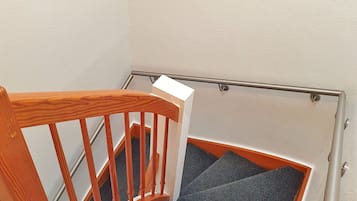 A wooden staircase with a handrail and carpeted steps.