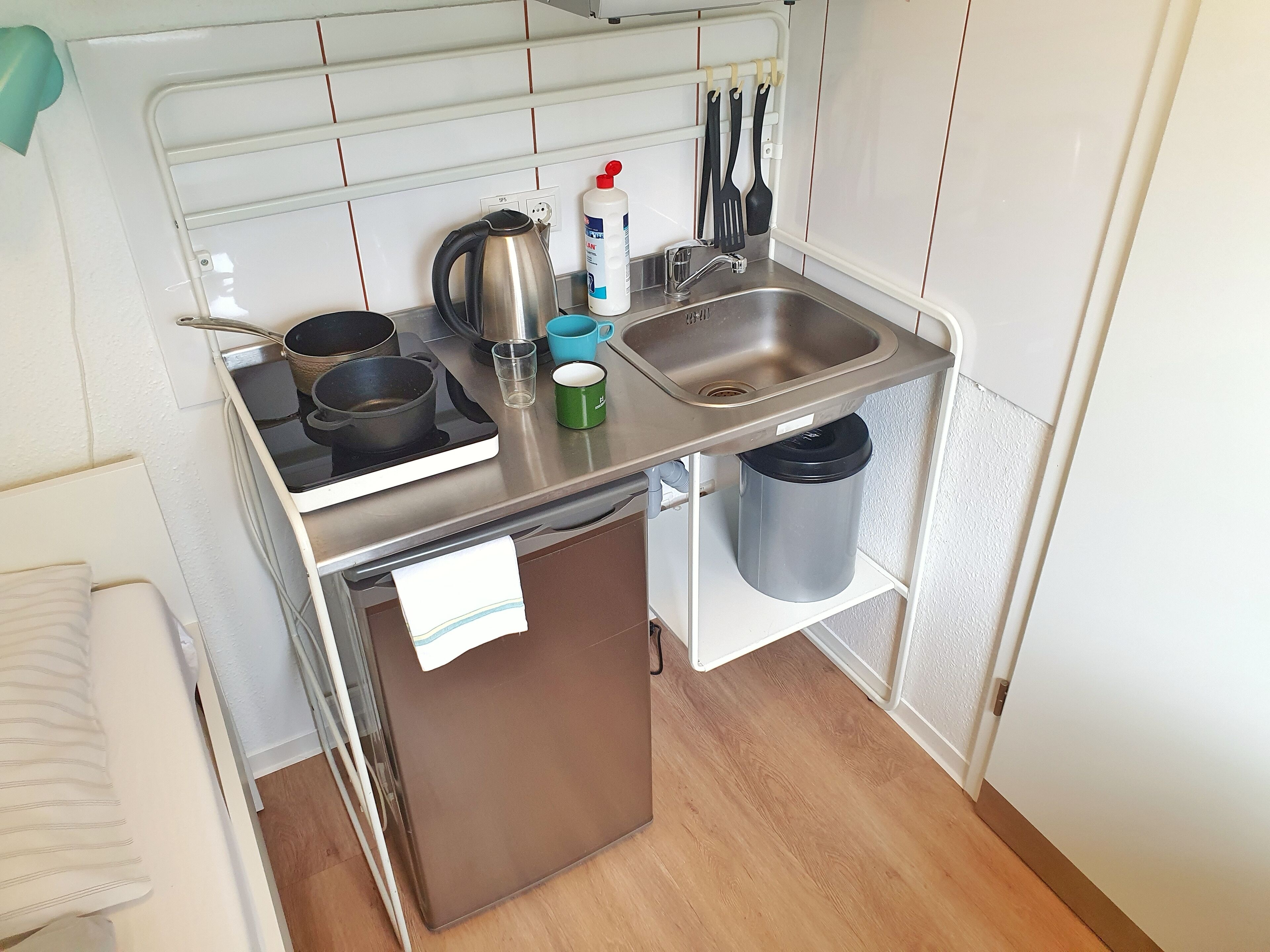 A compact kitchen with a sink, stove, and various utensils.