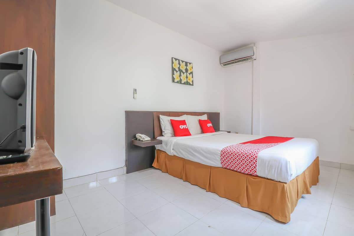 Een hotelkamer met een bed, een nachtkastje, een telefoon en een wandairconditioner.