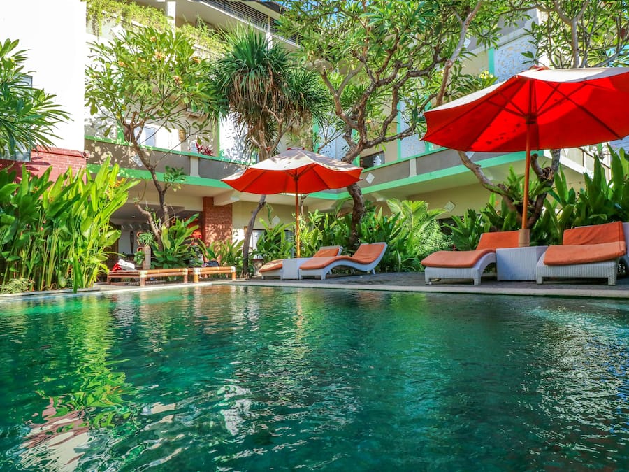 Una piscina al aire libre, sombrillas, sillones reclinables de piscina