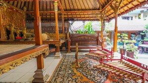 Un intérieur richement décoré, avec un sol à motifs, des meubles en bois et une structure de toit en chaume.