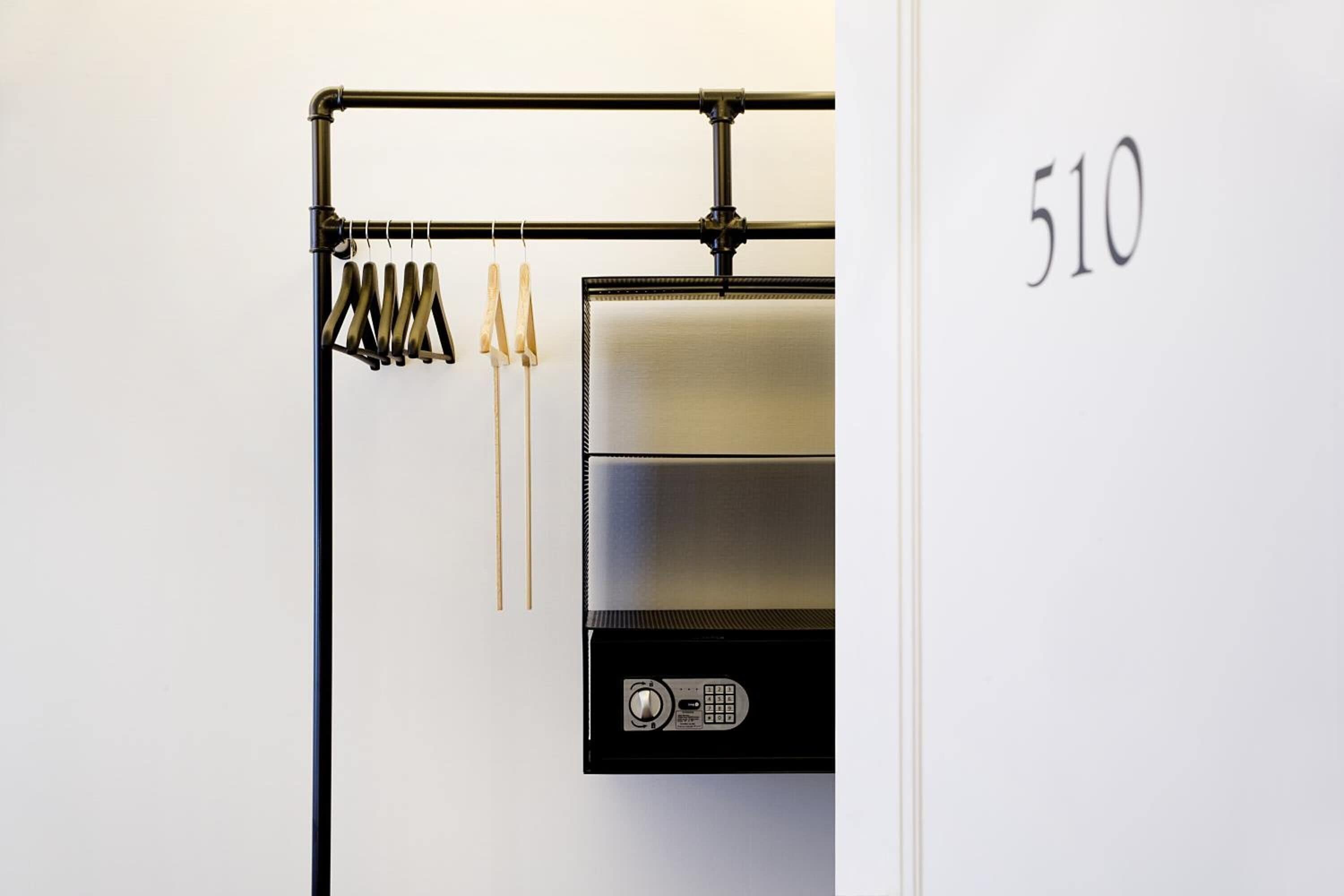A modern kitchen with a stainless steel range hood and a black metal rack with hanging utensils.