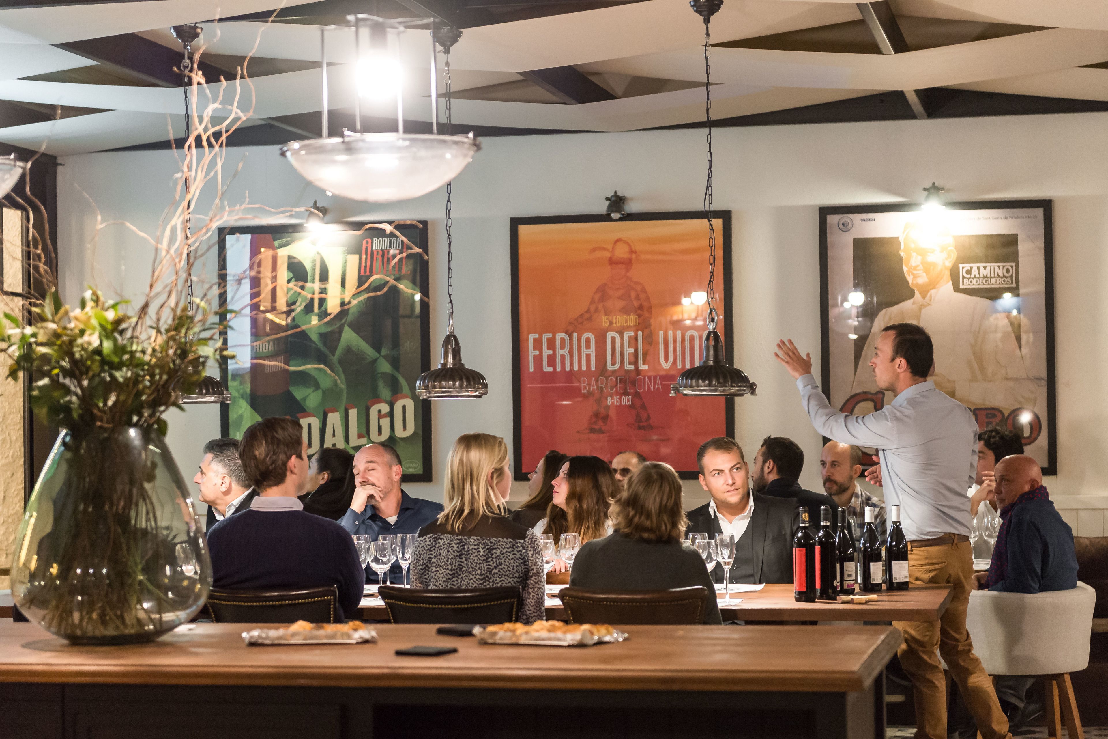 Ein Restaurantinneres mit Tischen, Stühlen, hängenden Lampen und Postern an der Wand.
