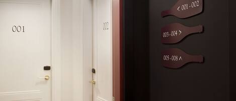 A hallway with doors labeled 001 and 002, and a wall with directional signs indicating room numbers 001-002, 003-004, and 005-008.