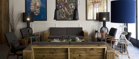 A modern living room with a sofa, chairs, and a wooden coffee table. There are three wall-mounted lamps and a large blue lamp on a stand.