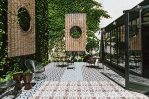 Un patio al aire libre con mobiliario de mimbre, suelo estampado y cerramiento de cristal.