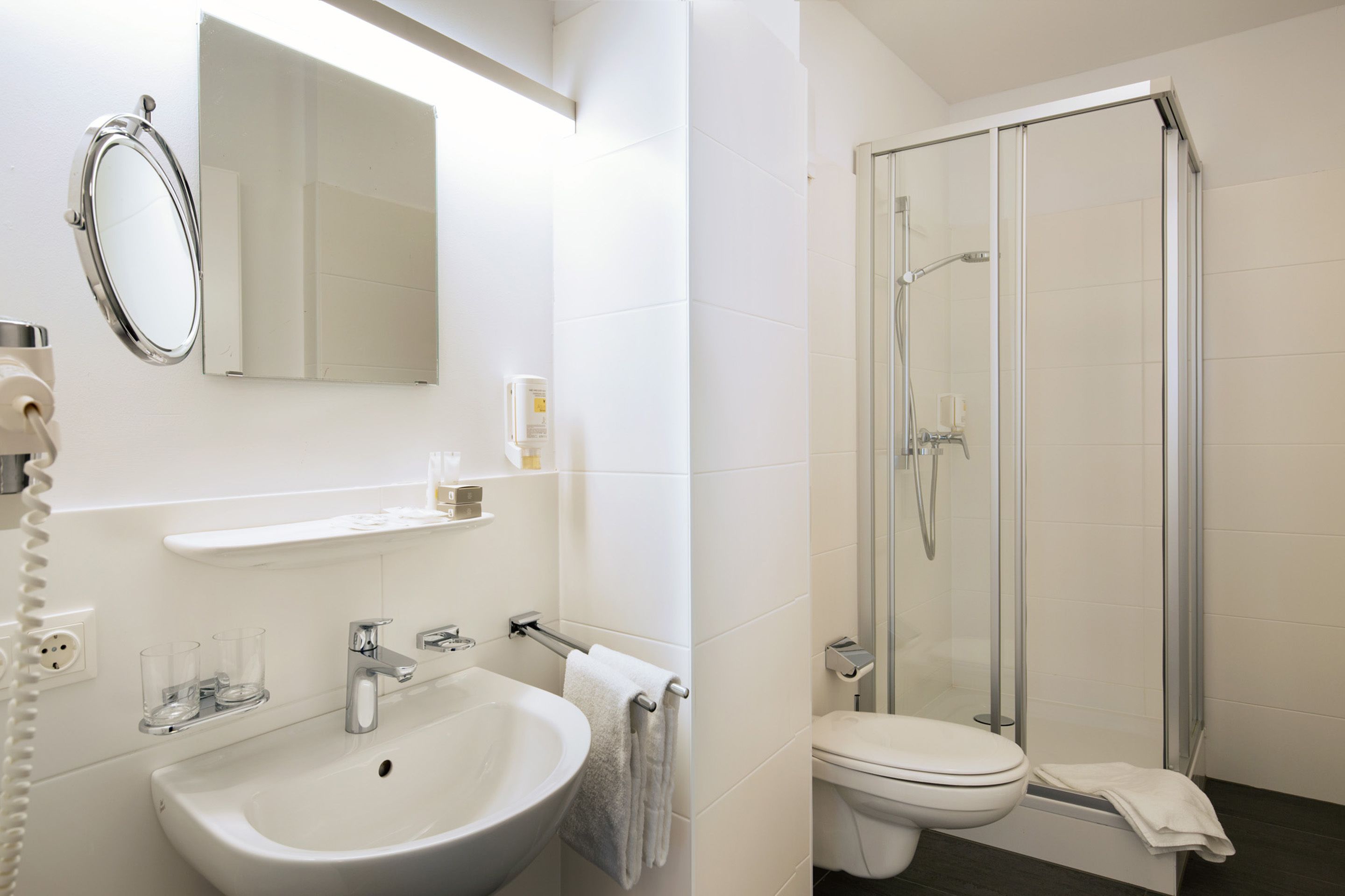A modern bathroom with a sink, mirror, and shower.