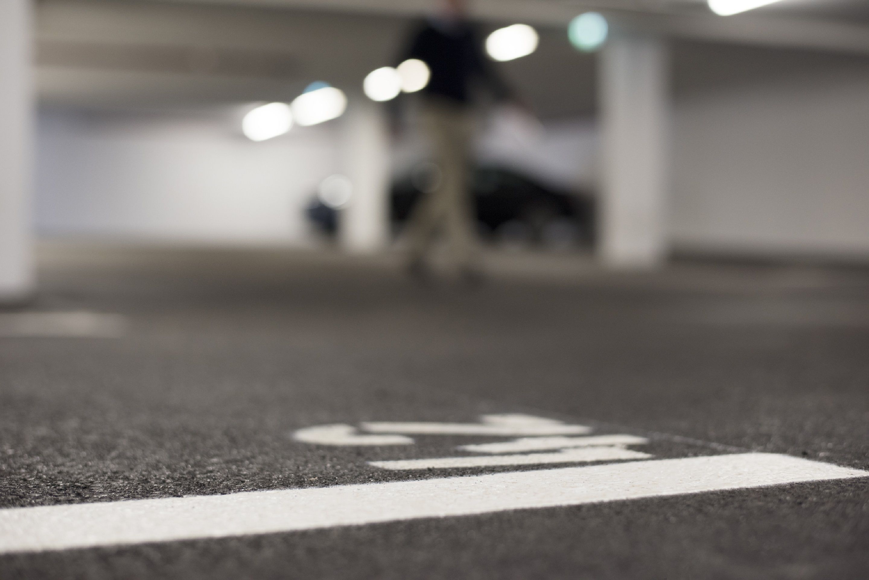 Un parking avec une flèche blanche indiquant la direction au sol.