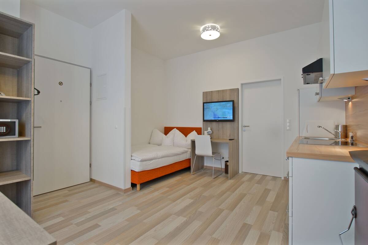 Een moderne slaapkamer met een bed, een televisie, een bureau en een kledingkast.
