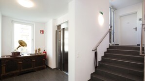 Un interior moderno con una escalera, un piano y un refrigerador.