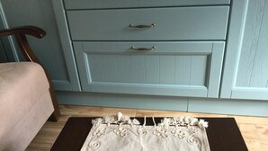 A bedroom with a bed, a light blue dresser with two drawers, and a decorative rug. - Silenos Boutique Hotel (Seferihisar)