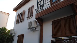 A building with wooden shutters, air conditioning units, and a balcony with a lattice design. - Silenos Boutique Hotel (Seferihisar)