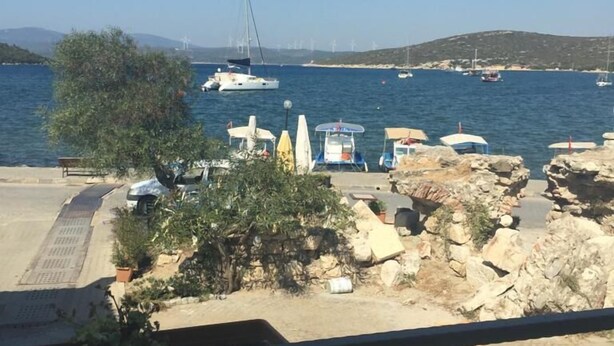 A coastal view with boats docked, rocky terrain, and a clear sky. - Silenos Boutique Hotel (Seferihisar)