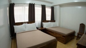 Une chambre avec deux lits, des têtes de lit en bois, une table de chevet en bois, une chaise et une petite table.