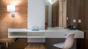 A modern bathroom with a wooden vanity, a white sink, a mirror, and a white chair. - AD Luxury Rooms & Suites (Athens)