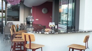 A modern bar area with a marble countertop, wooden chairs, and two glasses of white wine. - AD Luxury Rooms & Suites (Athens)