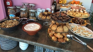 A buffet table with various food items, including pastries, fruits, and condiments. - AD Luxury Rooms & Suites (Athens)