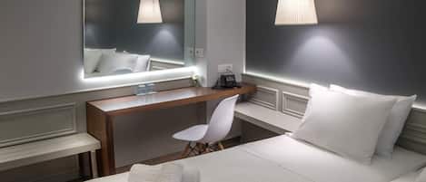 Ein modernes Hotelzimmer mit einem großen Bett, einem Schreibtisch, einem Stuhl und einem großen Spiegel.