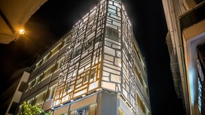 A modern building with a unique facade featuring a grid of windows and illuminated panels, likely a hotel or office building. - AD Luxury Rooms & Suites (Athens)