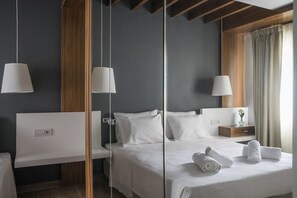 A modern hotel room with a large bed, bedside tables, a nightstand, and a mirror.
