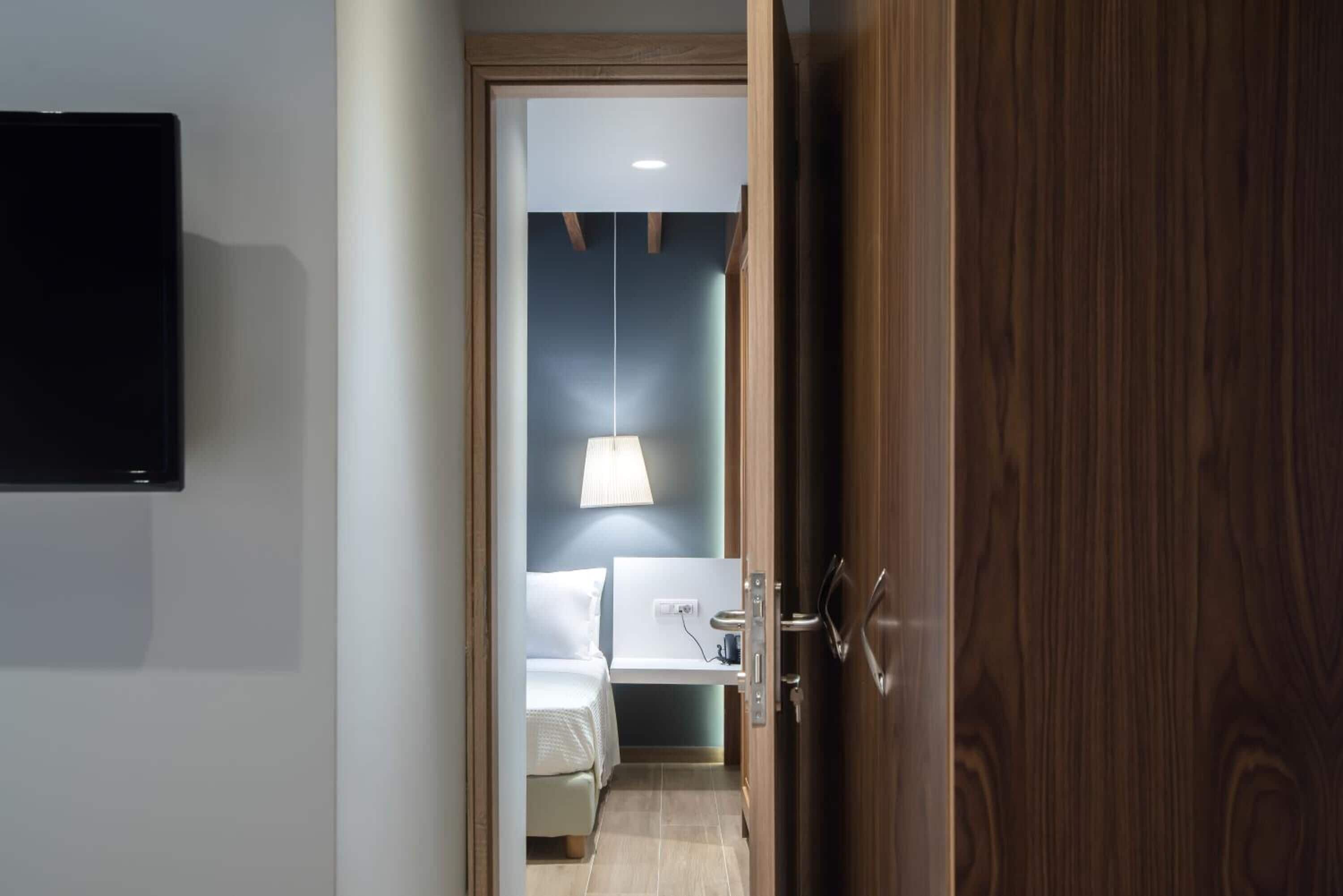 Une chambre d’hôtel équipée d’un lit, d’une table de chevet, d’une lampe et d’un téléviseur fixé au mur.