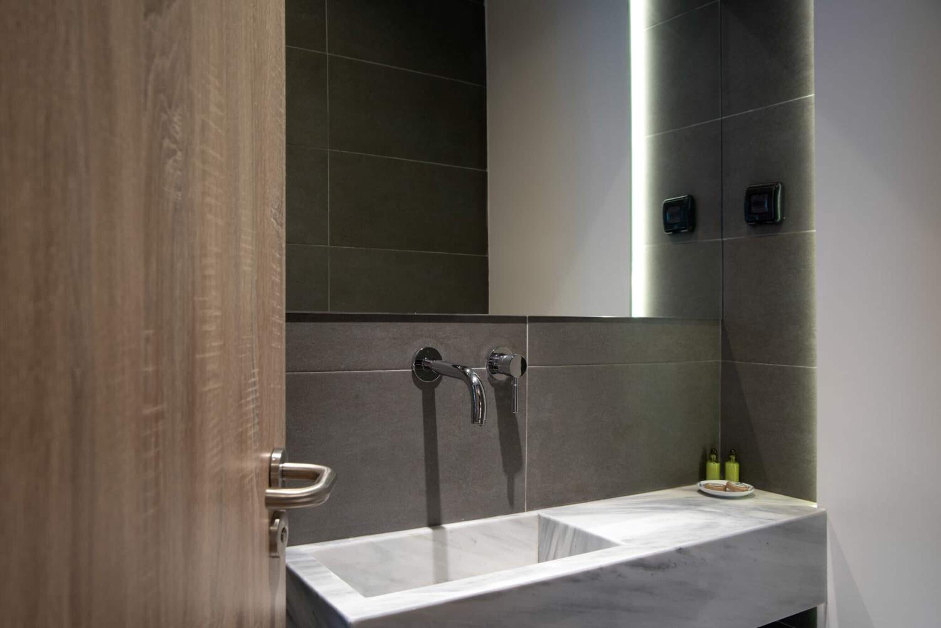 A modern bathroom with a marble sink, a shower with a handheld showerhead, and a towel rack.