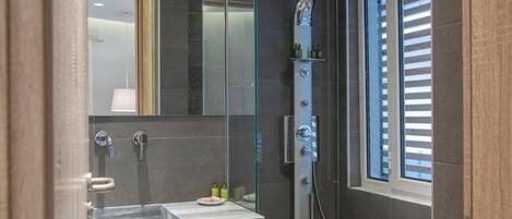 A modern bathroom with a glass-enclosed shower, a marble sink, and a large mirror.