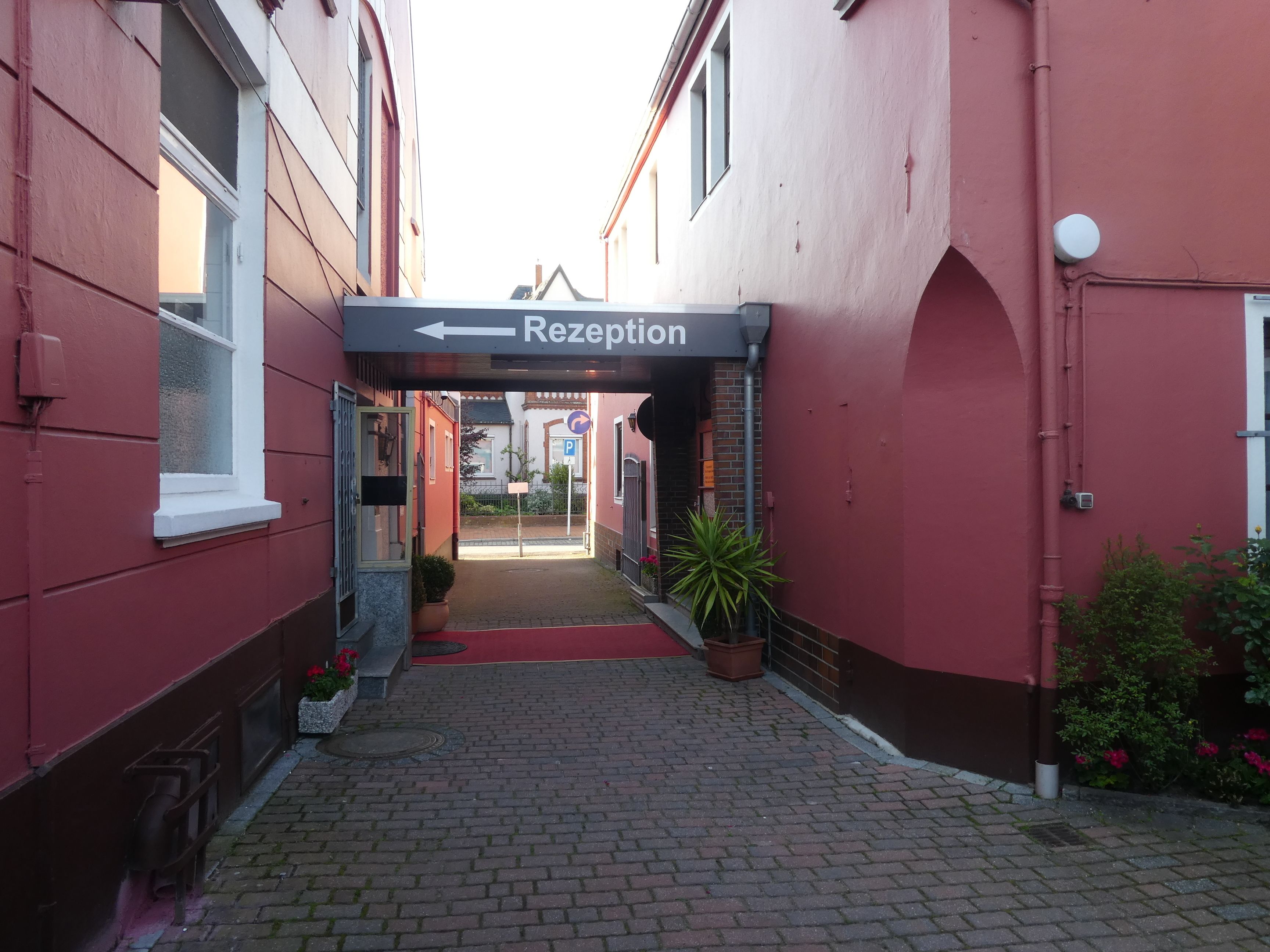 A red building with a reception sign and a paved walkway leading to a door.